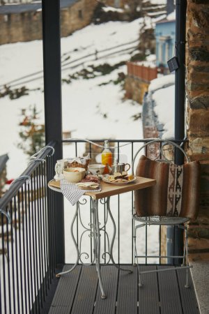 Winter breakfast on balcony overlooking snowy village.
