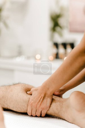 Téléchargez les photos : Vue détaillée d'un massage des jambes sur un homme, mettant l'accent sur la relaxation musculaire et les techniques thérapeutiques. - en image libre de droit
