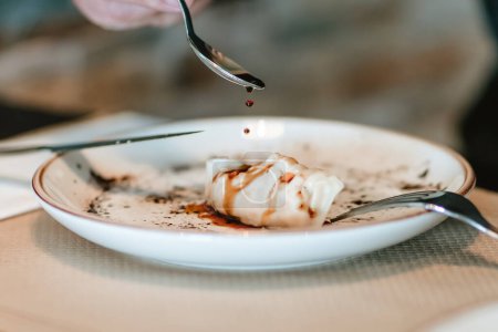 Photo for Detail shot of a spoon delicately drizzling sauce over a gyoza on a designer plate - Royalty Free Image