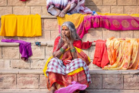Photo for Varanasi, Uttar Pradesh, India - November 2022: Portrait on an old south indian woman sitting near ganges ghat in traditional saree with open hair. Selective focus on eye and face. - Royalty Free Image