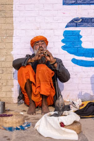 Téléchargez les photos : Varanasi, Uttar Pradesh, India - November 2022: Portrait of an unidentified old snake charmer male performing river side with snake in varanasi city for his survival and attract tourists. - en image libre de droit