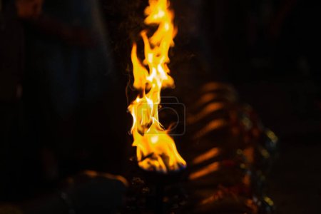 Téléchargez les photos : Fire flame at night with dark background during the ganga aarti rituals at river bank. - en image libre de droit