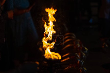 Téléchargez les photos : Fire flame at night with dark background during the ganga aarti rituals at river bank. - en image libre de droit