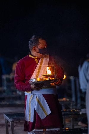 Photo pour Rishikesh, Uttarakhand, India - October 2022: Portrait of hindu male priest performing river Gange aarti with fire flame in hand at triveni ghat to worship river ganges. Ganga aarti performed in night - image libre de droit
