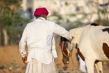 Foto de Pushkar, Rajasthan, India - November 2022: Pushkar Fair, camel trader in ethnic dress at fair ground during pushkar fair. - Imagen libre de derechos