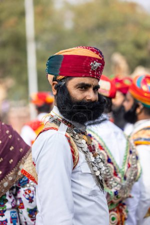 Foto de Bikaner, Rajasthan, India - January 2023: Camel Festival, Portrait of an young male with beard and moustache wearing white traditional rajasthani dress and turban. Rajput male of bikaner. - Imagen libre de derechos