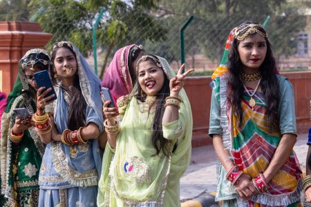Téléchargez les photos : Bikaner, Rajasthan, Inde - Janvier 2023 : Festival du chameau Bikaner, Groupe de jeunes belles filles en tenue traditionnelle et bijoux du rajasthan tout en participant à la parade. Concentration sélective. - en image libre de droit