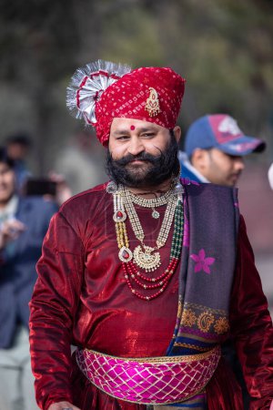 Foto de Bikaner, Rajastán, India - Enero 2023: Punjabi Bhangra, Retrato de un joven sikh masculino con un vestido tradicional de colores punjabi y turbante realizando danza bhangra con sonrisa en un festival de camellos con enfoque - Imagen libre de derechos