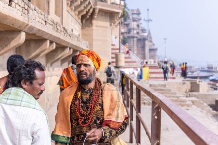Foto de Varanasi, Uttar Pradesh, India - Noviembre 2022: Retrato de sadhu baba indio no identificado caminando sobre ghat cerca de las bandas fluviales en la ciudad de varanasi con vestimenta tradicional. Varanasi es la ciudad más antigua y santa. - Imagen libre de derechos
