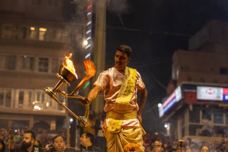 Foto de Varanasi, Uttar Pradesh, India - Noviembre 2022: Ganga aarti, Retrato de un joven sacerdote realizando pandillas fluviales aarti vespertino en Dashashashwamedh Ghat en traje tradicional con rituales hindúes sanatán. - Imagen libre de derechos