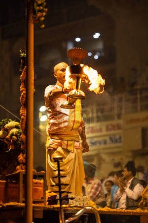 Foto de Varanasi, Uttar Pradesh, India - Noviembre 2022: Ganga aarti, Retrato de un joven sacerdote realizando pandillas fluviales aarti vespertino en Dashashashwamedh Ghat en traje tradicional con rituales hindúes sanatán. - Imagen libre de derechos