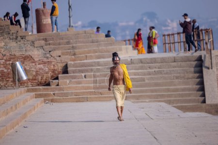 Foto de Varanasi, Uttar Pradesh, India - Noviembre 2022: Retrato de sadhu baba indio no identificado en el ghat assi en el ghat cerca de las bandas fluviales en la ciudad de varanasi con vestimenta tradicional. - Imagen libre de derechos