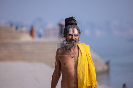 Foto de Varanasi, Uttar Pradesh, India - Noviembre 2022: Retrato de sadhu baba indio no identificado caminando sobre ghat cerca de las bandas fluviales en la ciudad de varanasi con vestimenta tradicional. Varanasi es la ciudad más antigua y santa. - Imagen libre de derechos