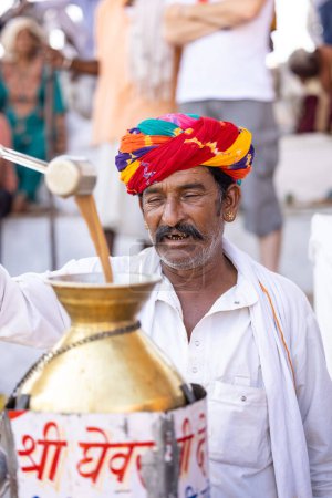 Téléchargez les photos : Pushkar, Rajasthan, Inde - Novembre 2022 : Foire de Pushkar, Portrait d'un vieil homme rajasthani avec en robe traditionnelle blanche et turban coloré au terrain de foire de pushkar. - en image libre de droit