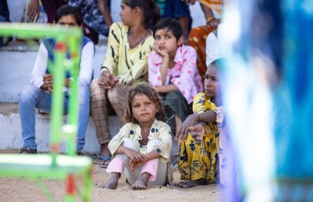Téléchargez les photos : Pushkar, Rajasthan, Inde - Novembre 2022 : Foire de Pushkar, Portrait de jeunes enfants sur un terrain de foire en robes colorées regardant les activités pendant la foire. - en image libre de droit