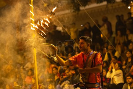 Photo for Varanasi, Uttar Pradesh, India - November 2022: Ganga aarti, Portrait of an young priest performing river ganges evening aarti at assi Ghat in traditional dress with fire flame and rituals. - Royalty Free Image