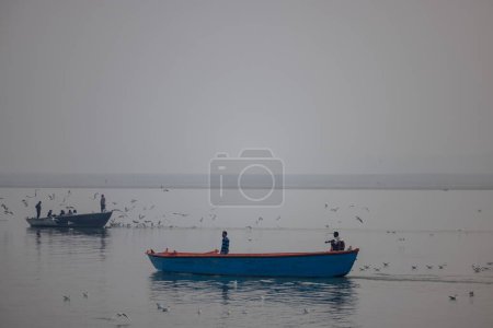 Téléchargez les photos : Varanasi, Uttar Pradesh, Inde - Novembre 2022 : Les touristes profitent d'une promenade en bateau dans le fleuve Ganges avec le troupeau de goélands marins à varanasi. - en image libre de droit