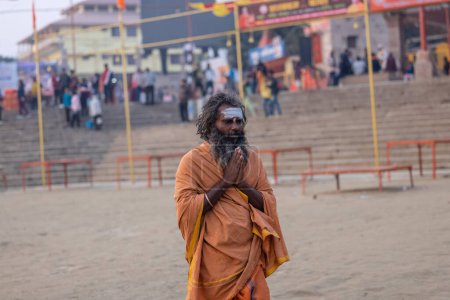 Téléchargez les photos : Varanasi, Uttar Pradesh, Inde - Novembre 2022 : Portrait de sadhu baba indien non identifié sur le ghat près de la rivière Ganges dans la ville de varanasi au lever du soleil. - en image libre de droit