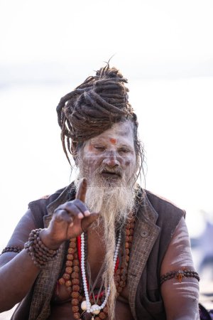 Téléchargez les photos : Varanasi, Uttar Pradesh, Inde - Novembre 2022 : Portrait de sadhu baba indien non identifié sur le ghat près de la rivière Ganges dans la ville de varanasi au lever du soleil. - en image libre de droit