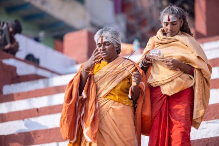 Photo for Varanasi, Uttar Pradesh, India - November 20 2022: Portrait of Unidentified Indian holy sadhu female walking at kedar ghat near river ganges in varanasi city in traditional saffron dress. - Royalty Free Image