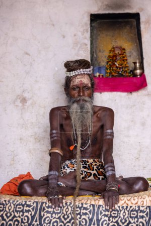 Foto de Varanasi, Uttar Pradesh, India - 20 de noviembre de 2022: Retrato de un hombre sadhu sagrado indio no identificado con largas sesiones de barba blanca en el ghat dashashashwamedh cerca de las pandillas de los ríos - Imagen libre de derechos