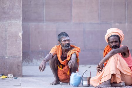 Foto de Varanasi, Uttar Pradesh, India - 20 de noviembre de 2022: Retrato de sadhu santos indios no identificados sentados en el ghat dashashwamedh cerca de las pandillas fluviales en la ciudad de varanasi con vestimenta tradicional - Imagen libre de derechos