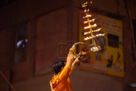 Photo for Varanasi, Uttar Pradesh, India - November 20 2022: Ganga aarti, Portrait of young priest performing holy river ganges evening aarti at dashashwamedh ghat in traditional dress with hindu rituals. - Royalty Free Image
