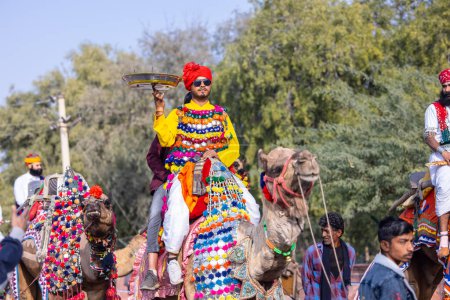 Téléchargez les photos : Bikaner, Rajasthan, Inde - 13 janvier 2023 : Festival du chameau, Portrait d'un jeune homme rajasthani avec barbe et moustache portant une robe traditionnelle blanche rajasthani et turban à dos de chameau, - en image libre de droit