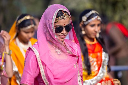 Foto de Bikaner, Rajastán, India - 13 de enero de 2023: Festival del Camello Bikaner, Retrato de una joven hermosa en vestido tradicional rajastaní con gafas y joyas mientras participaba en el desfile. - Imagen libre de derechos