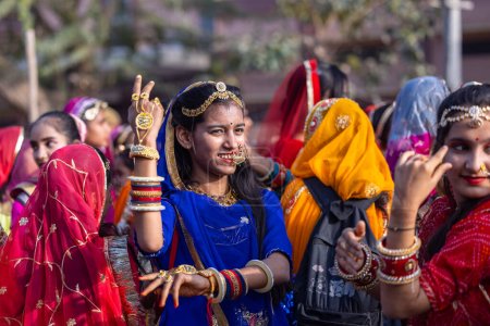 Photo for Bikaner, Rajasthan, India - January 13 2023: Camel Festival Bikaner, Group of young beautiful girls in traditional rajasthani dress and jewellery while participating in the parade. Selective focus. - Royalty Free Image