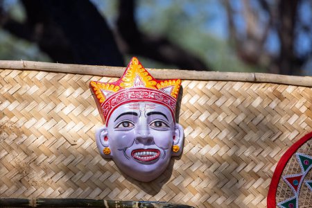 Handgemachtes farbenfrohes Gesichtsmasken-Souvenir im Stammeslook, das auf schlichtem Hintergrund hängt. Selektiver Fokus auf Objekt.