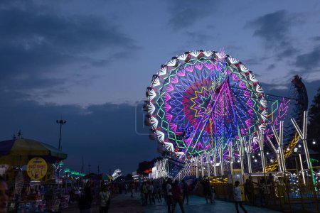 Photo for Ghaziabad, Uttar Pradesh, India - October 05 2022: Tourists enjoying joint wheel ride at fair ground during the annual dussehra fair in night. - Royalty Free Image