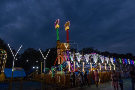 Photo for Ghaziabad, Uttar Pradesh, India - October 05 2022: Tourists enjoying joint wheel ride at fair ground during the annual dussehra fair in night. - Royalty Free Image