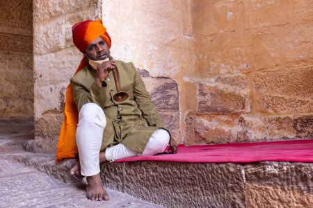 Téléchargez les photos : Jodhpur, Rajasthan, Inde - 25 septembre 2021 : Mehrangarh Fort, Portrait de l'artiste jouant de l'instrument de musique dans la robe traditionnelle Rajasthani pour divertir les touristes dans les locaux du fort. - en image libre de droit