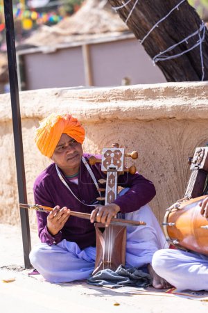 Photo for Faridabad, Haryana, India - 4 February 2023: Portrait of male artist of haryana playing musical instrument during surajkund craft fair to entertain tourists. - Royalty Free Image