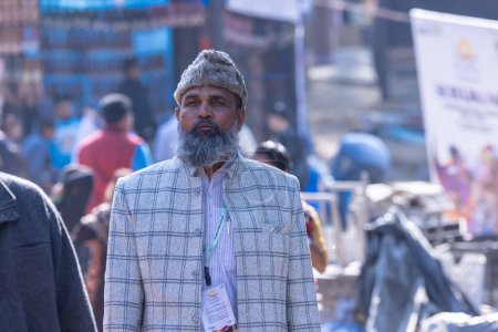 Foto de Faridabad, Haryana, India - 4 de febrero de 2023: Retrato de un anciano musulmán con sombrero caliente de invierno en la cabeza caminando en el recinto ferial de Surajkund. - Imagen libre de derechos