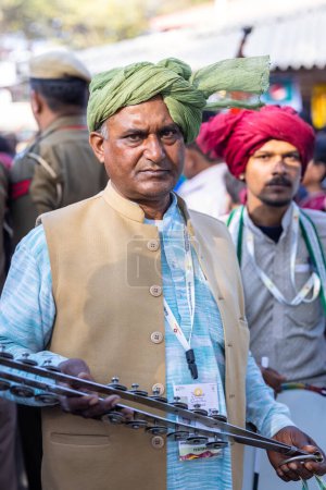 Téléchargez les photos : Faridabad, Haryana, Inde - 04 février 2023 : Portrait d'un artiste masculin de l'haryana jouant de l'instrument de musique lors d'une foire artisanale surajkund pour divertir les touristes. - en image libre de droit
