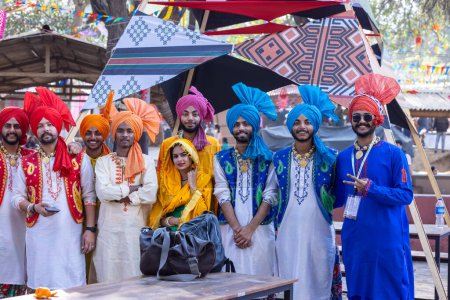 Téléchargez les photos : Faridabad, Haryana, Inde - 04 février 2023 : Groupe de sikhs masculins et féminins vêtus de vêtements traditionnels punjabis et de turban lors d'un spectacle de danse bhangra à la foire artisanale de surajkund - en image libre de droit