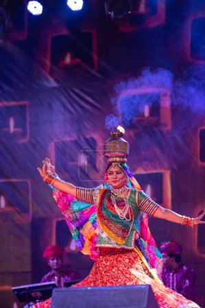 Photo for Pushkar, Rajasthan, India - November 05 2022: Female artist performing rajasthani folk dance Ghoomar in traditional colorful dress and metal pot with fire on head in Pushkar fair. Selective focus - Royalty Free Image