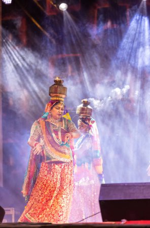 Photo for Pushkar, Rajasthan, India - November 05 2022: Female artists performing rajasthani folk dance Ghoomar in traditional colorful dresses and metal pots with fire on heads in Pushkar fair. Selective focus - Royalty Free Image