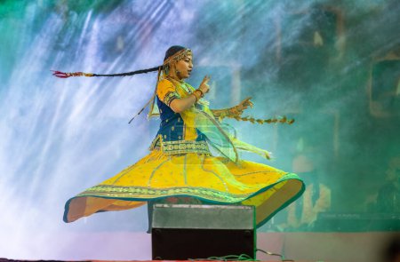 Téléchargez les photos : Pushkar, Rajasthan, Inde - novembre 05, 2022 : Portrait d'une jeune belle artiste féminine dansant pendant la foire du pushkar en robe rajasthani ethnique colorée. Focus sélectif sur l'artiste - en image libre de droit