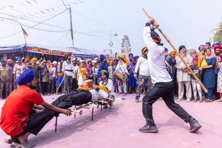 Téléchargez les photos : Anandpur Sahib, Punjab, Inde - 19 mars 2022 : Portrait d'un homme sikh (Nihang Sardar) pratiquant l'art martial en tant que culture lors de la célébration de Hola Mohalla à Anandpur Sahib pendant le festival holi - en image libre de droit