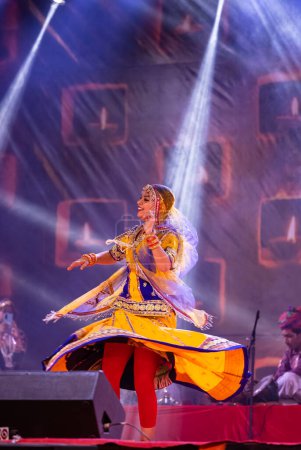 Foto de Pushkar, Rajastán, India - 05 de noviembre de 2022: Retrato de una joven y hermosa artista realizando danza durante la feria de pushkar en colorido vestido rajastaní étnico. Enfoque selectivo en artista - Imagen libre de derechos