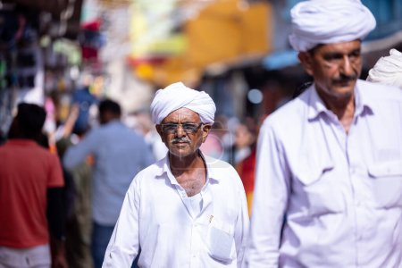 Téléchargez les photos : Pushkar, Rajasthan, Inde - 06 novembre 2022 : Foire de Pushkar, Portrait d'un vieil homme rajasthani avec turban blanc jouissant à la foire de pushkar - en image libre de droit