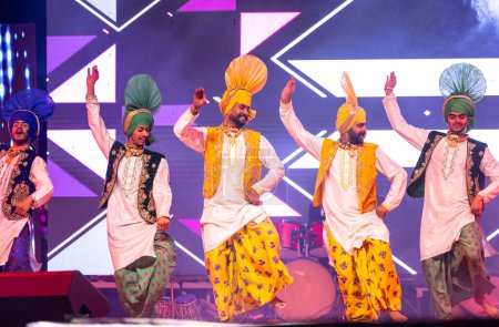 Foto de Bikaner, Rajastán, India - 14 de enero de 2023: Grupo de artistas punjabi de punjab que bailan bhangra con ropa colorida tradicional en el festival de camellos bikaner - Imagen libre de derechos