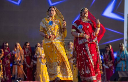Foto de Bikaner, Rajastán, India - 14 de enero de 2023: Retrato de mujeres indias hermosas jóvenes en vestidos de rajasthani lehenga choli étnicos que participan en el desfile de moda Miss Marwar durante el festival de camellos de ciclista - Imagen libre de derechos
