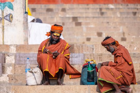 Téléchargez les photos : Varanasi, Uttar Pradesh, Inde - 05 mars 2023 : Portrait de vieux sadhu baba en habits traditionnels assis sur des ghats près de Ganges à Varanasi - en image libre de droit