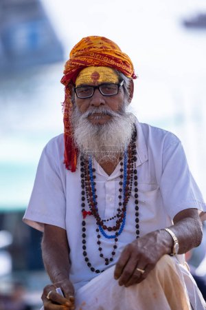 Photo for Varanasi, Uttar Pradesh, India - March 05 2023: Portrait of old holy sadhu baba in traditional dress sitting on the ghats near ganges in varanasi. Kashi  oldest and holy city - Royalty Free Image