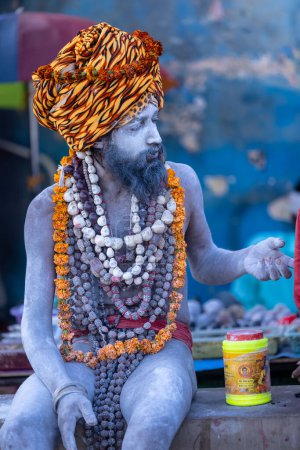Photo for Varanasi, Uttar Pradesh, India - March 05, 2023: Portrait of old holy naga sadhu baba with ash on his face and body sitting on the dashashwamedh ghat near ganges in varanasi - Royalty Free Image