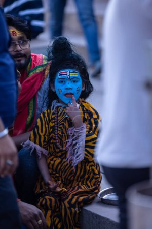 Téléchargez les photos : Varanasi, Uttar Pradesh, Inde - 05 mars 2023 : Masan Holi, Portrait d'un jeune garçon habillé comme shiva de seigneur avec le visage peint au ghat de dashashwamedh à varanasi pendant le festival de holi. - en image libre de droit
